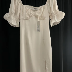 Gathered chest slit mini Dress  - Säljer denna satin klänningen i färgen krämvit från NA-KD i storlek 38. Aldrig använd och prislappen sitter fortfarande på. I toppen skick💕säljer för 199 då orginalpriset är 400 kr 
