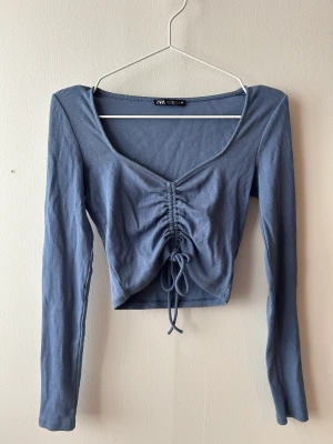 Zara top - En kort top med långa ärmar från Zara. Knytdetalj vid magen. Storlek XS/S