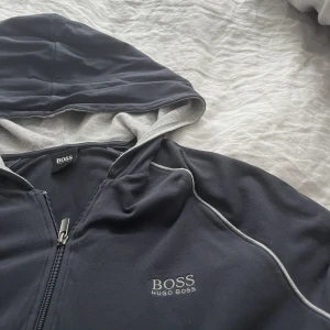 Hugo boss zip hoodie - En mörkblå Hugo boss ziphoodie använd Max 3 ggr och säljs pga att det inte är min stil och inte kommer till användning, inga fel på den o pris går att diskutera