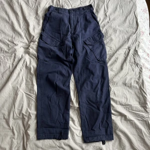 Vintage navy blue Combat Trousers - Marinblå miltiärbyxa, US eller UK. Med snörning i bensluten.  Midja ca 31-32. Köpta på Broadway & Sons i Göteborg. Klassiskt hål i skrevet men lätt att lappa då där inte är några sömmar.