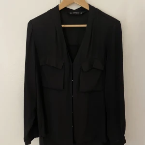 Skjorta  - En fin skjorta från Zara. Den har fickor runt brösten och har dessutom guldknappar. Den har också en slits i ryggen så den är mycket cool