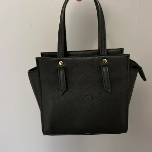 Svart liten väska  - Säljer den här jättesöta väskan! Man får plats med sin mobil (iPhone 13) och andra saker💕Väskan har inga tecken på användning, hör av dig vid frågor💕Köpte för 250 men säljer för 50kr 💕