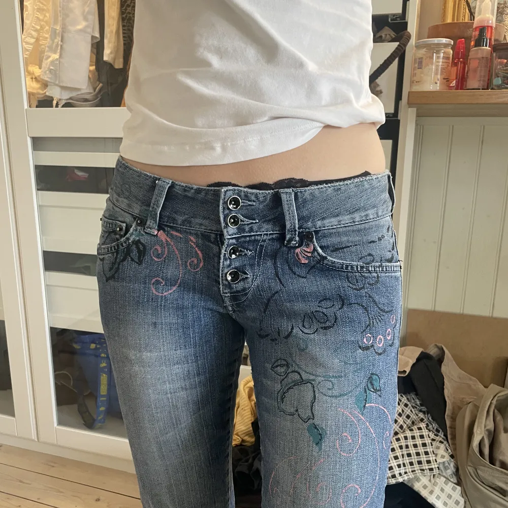 LÅGMIDJADE JEANS MED FINA DETALJER PÅ     SKICK: Byxorna är i bra skick och har inga defekter.                                          MÅTT: Midjemåttet: 76cm Innerbensmått: 77cm. Jeans & Byxor.