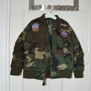 Top gun-jacka 110/116 - Jacka i top gun-stil. Sparsamt använd utav ett barn. Ingenting att anmärka på.