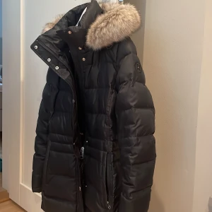 Dunjacka - En liten lagning pga av en liten reva. Syns knappt . Annars i jättefint skick. På bilden ser ni lagningen . Avtagbar luva !Nypris 2800kr