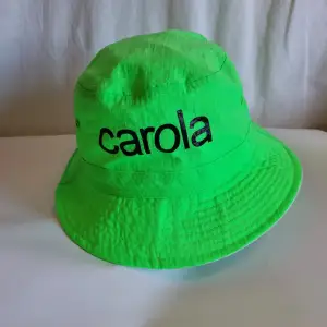 Neongrön hatt med Carola tryck på ena sidan Hatten är vändbar One size/ en storlek passar alla  * Helt oanvänd *
