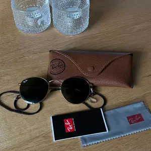 RayBan solglasögon som jag köpt för flera år sen i butik. Fint skick. Guldiga runt om. Ingår  - Fodral till solglasögon  - Band till - Tvättduk (oanvänd och oöppnad) - Nån manual av nått slag