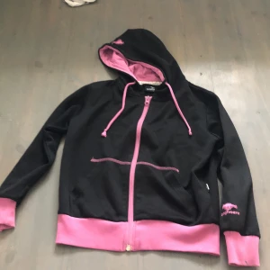 Svart och rosa luvtröja - Jag säljer en svart och rosa hosdie. Två fickor fins. Den är i bra skick förutom att den är lite nopprig. Stolek 130.