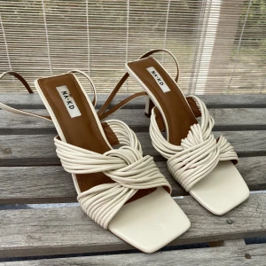 Vita klackskor  - Fina somriga klackskor från NA-KD. Är endast använda en gång av mig. Har en fläck i hälen ( se bild 3). Priset är inklusive frakt 