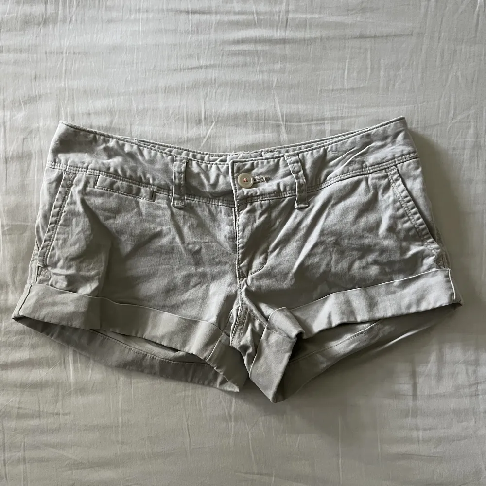 Supersöta vintage beige-gråa lågmidjade mini shorts med unika bakfickor. Begagnat skick, men inga fläckar eller hål! Midjemått mätt rakt över: 37cm, längd: 20cm. Storlek 34🫶💕. Shorts.