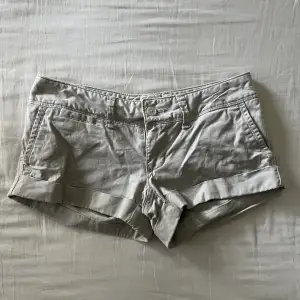 Supersöta vintage beige-gråa lågmidjade mini shorts med unika bakfickor. Begagnat skick, men inga fläckar eller hål! Midjemått mätt rakt över: 37cm, längd: 20cm. Storlek 34🫶💕