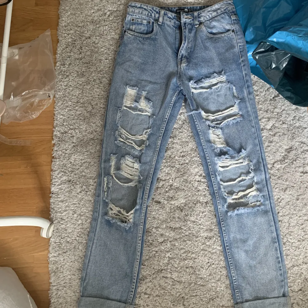 Högmidjade slitna blå jeans från Boohoo i stlk 36. De är lite för små i längden för mig som är 175cm (kolla andra bilden). Har använt dem 1-2 ggr. De är slutsålda på hemsidan. . Jeans & Byxor.