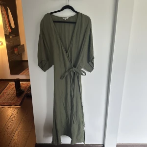 Linneklänning Grön Indiska S - Säljer min väldigt smickrande omlott midiklänning i linne från Indiska. Köpt 2021 och använd endast en gång. 