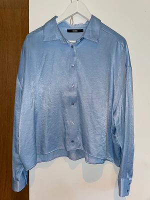 Glansig skjorta  - Glansig blå skjorta från bikbok. Fint skick, nästan inte använd. 