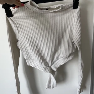 Vit kroppad tröja  - Vit kroppad tröja med ett fint och flattering kors runt magen. Storlek XS