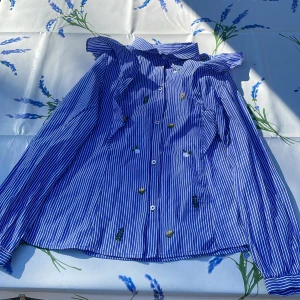 Randig blå skorta! - Blå skorta med blomm detaljer och volang. Använt en gång och mycket bra kvalitet! Från Zara! Storlek 140 10-11! Ha en härlig dag eller kväll!😃👕