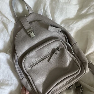 Söt ryggsäck - Säljer denna söta lilla grå ryggsäcken. Använd endast en gång och är som ny. Får plats med rätt mycket trots liten storlek🎒😎💕💕