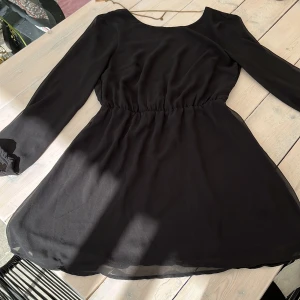 Klänning - Klänning med öppen rygg i silkigt material. Bra skick. 