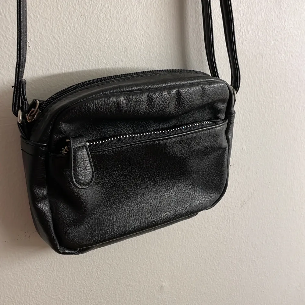 Testar att sälja denna lilla svarta handväska, då jag ej använder den. Märke vet jag ej, då jag köpte den för många år sedan. Däremot är den knappt använd och skulle säga att den är i nyskick. Har en ficka på utsidan och även en ficka inuti. Väldigt fin🫶🖤. Väskor.