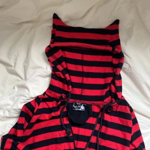 randig hoodie - Röd och svartrandig hoodie med typ horn. Hål för tummarna. Dragkedjan är sönder så man har den antingen öppen eller som på andra bilden. Går säkert att laga.