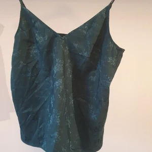 Grönt linne med blommor - Mörkgrönt linne med blommiga detaljer, hela linnet skimrar beroende på ljuset 💚 justerbara axelband 