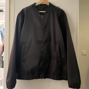 Oversized bomberjacka  - Oversized bomberjacka från H&M i glansig svart.   Storlek: XL 100% Polyester  Använd vid ett tillfälle, perfekt skick   