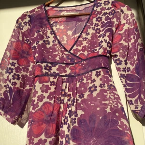 Blommig meshblus med knytning - Blommig blus med i så härliga färger🌸 Den är i tunt mechtyg och har knytning i ryggen så går att justera i passform. Säljer då den inte längre är min stil💕