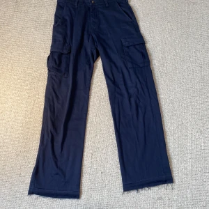 Blåa cargo byxor - Fina blåa cargo byxor. Längd 109cm. Midja 42cm. Se bild