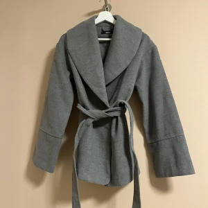 Grå kappa  - En nyköpt grå kappa från Bikbok i storlek XS, passar även S. Säljer pga att det ej passar min stil. Använt kappan 2 gånger endast. Nypris på kappan var 699 kr och köptes för 2 veckor sedan. 
