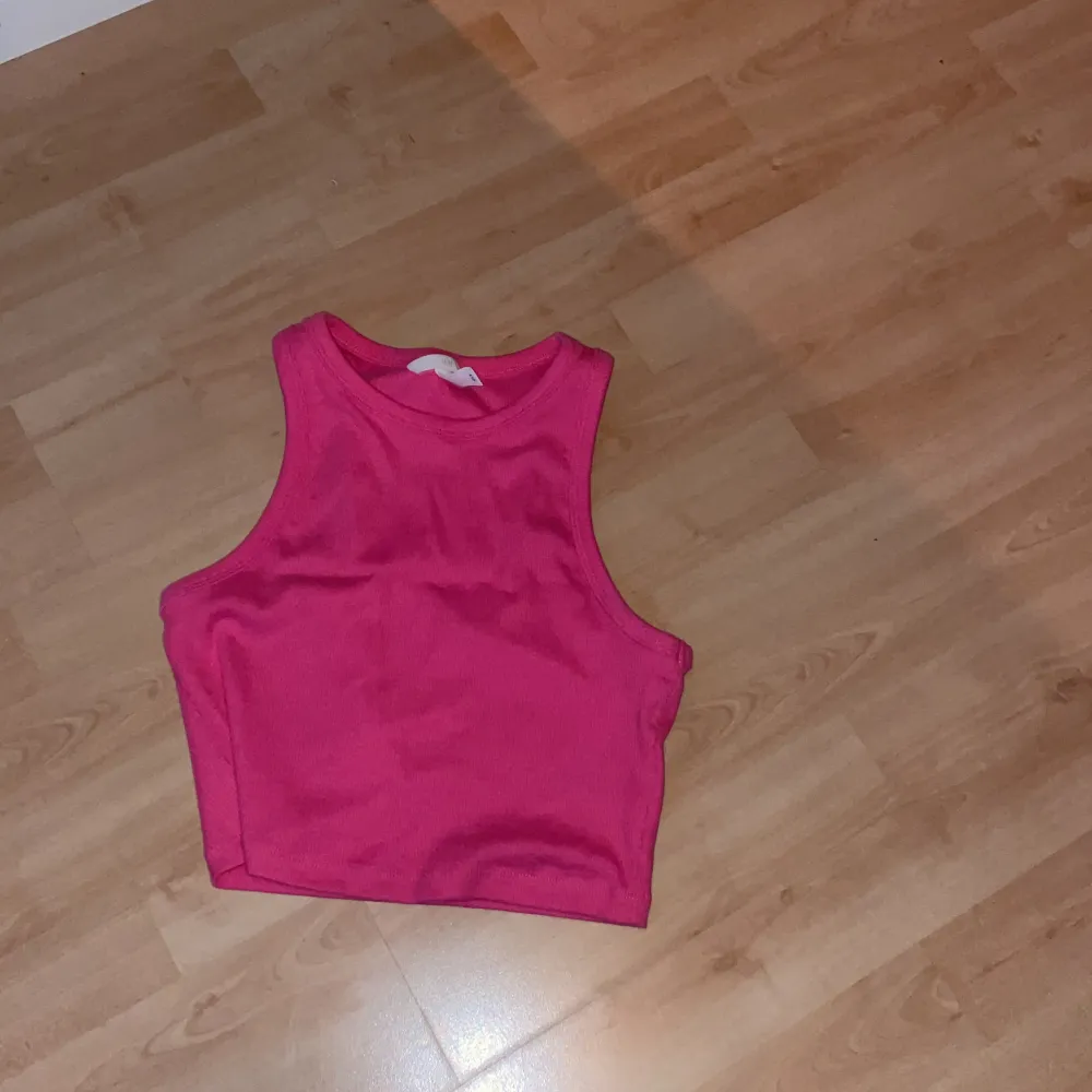Ett kortare linne med stark rosa färg som är ribbat. . Toppar.