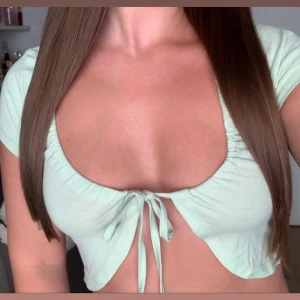 Croppad topp med dragsko - Croppad kortärmad topp med dragsko i strl XS. Färg: mintgrön/ljusgrön. Helt ny med lappar på! Köparen står för eventuella fraktkostnader.