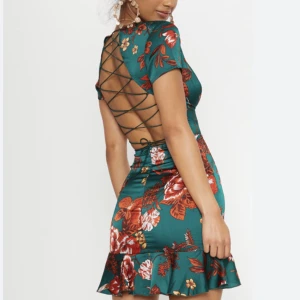 Grön blommig öppen rygg klänning - Grön, blommig och öppenrygg. Satin. Använd ett fåtal gånger. Kan skicka bild med klänning på! 