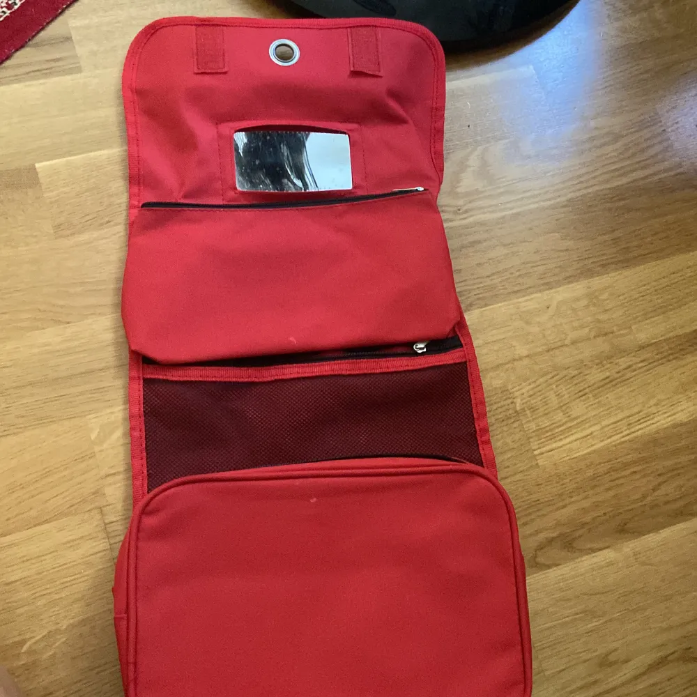 En röd necessär som går att vika upp och har flera olika fack. Den går även att hänga upp!💓. Väskor.