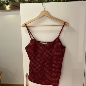 Mörkrött linne - Säljer ett mörkrött, prickigt linne från Mango i storlek S. Använd endast ett par gånger! Axelbanden är insydda som syns på bilden men är väldigt lätt att sprätta och sy om om man vill. Jättegulligt linne men inte min stil längre. Fint skick!