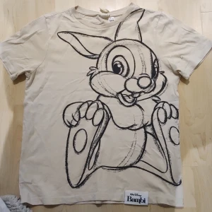 T-shirt med Stampe från Bambi - En enkel ljus beige T-shirt med ett skissat tryck av Stampe från Disney filmen Bambi