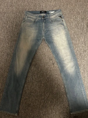Ljusblå Replay jeans - Säljer ett par ljusblå jeans från Replay med snygga slitningar och tvättade detaljer på låren. Klassisk femficksmodell med raka ben och normal midja. Perfekta för en avslappnad och trendig look.