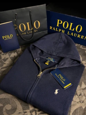Mörkblå hoodie från Polo Ralph Lauren - Snygg mörkblå hoodie från Polo Ralph Lauren med dragkedja framtill och klassisk vit logga broderad på bröstet. Hoodien har huva med dragsko och mjukt material som känns skönt mot huden. Perfekt för en avslappnad och stilren look.tillbehör ingår inte bara tröjan för priset⚠️‼️🚨Storlekn är XL men för barn. Så för typ 160-170cm