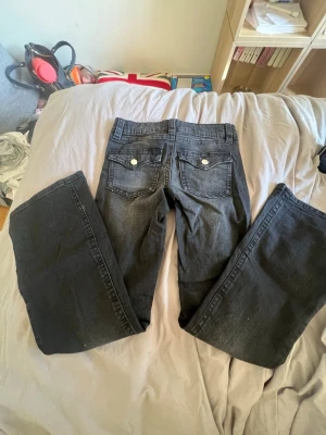 Svarta bootcut jeans - Säljer ett par svarta bootcut jeans med snygga fickdetaljer bak och silverfärgade knappar.💕💘