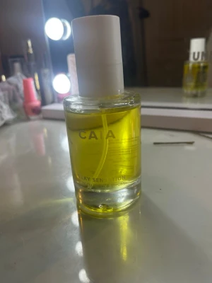 CAIA Silky Sensation parfym - En stilren body oil från CAIA med namnet Silky Sensation. Flaskan är rund och genomskinlig med en vit kork och innehåller en gul body oil som ej färgar av sig på huden. Perfekt för dig som gillar fräscha och eleganta dofter. !varan är endast testad och säljs då jag inte gillade vanilj doften!