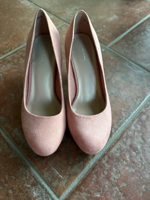 Rosa pumps med bred klack - Snygga rosa pumps i mockaimitation med rund tå och bred klack. Skorna har en klassisk siluett och en mjuk, matt finish som ger en trendig look. Perfekta för dig som vill ha både stil och komfort i ett par klackar.