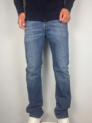 Blå raka jeans från Levi's - Levis 501 med lätt bootcut. Färg: Blå med fades | Modell: 501 | Storlek: W30 L34 | Vintage Premium Jeans . Som ni ser alldeles för liten i midjan och lår för mig som väger 82 kg. Okej i längden på mig som är 189 cm. A: Midja: 38,5 cm B: 110 cm C: 20,5 cm D: 26cm Tveka inte att höra av dig minsta fråga eller fundering! Skickas snabbt!