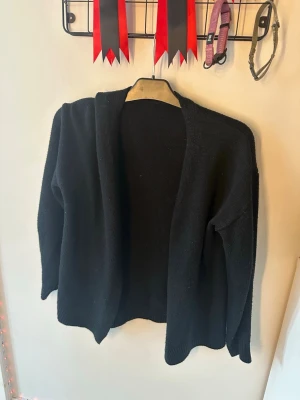 Svart öppen kofta från SHEIN - En svart, öppen kofta från SHEIN i mjukt stickat material. Koftan har lång ärm och enkel, avslappnad passform utan knappar eller dragkedja. Perfekt att slänga över en t-shirt eller topp för en chill look.