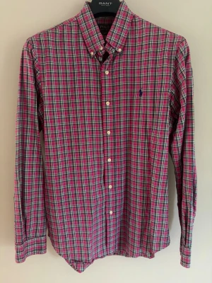 00s Polo Ralph Lauren rutig skjorta - Klassisk rutig skjorta från Polo Ralph Lauren i storlek M. Slim fit och 100% bomull. Rosa med blå gröna och vita detaljer. Mörkblå ikonisk logga broderad fram på bröstet. Vita knappar. Mycket bra skick, inga skador eller annat.