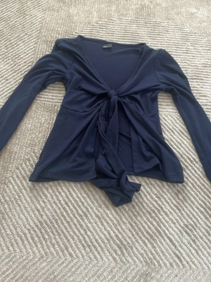 Mörkblå långärmad topp Gina Tricot - En populär marinblå tunn långärmad men Knutsen i fram och öppen mage. Perfekt för sommar och nästan aldrig använd kontakta om intresserad!