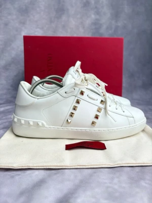 Valentino Rockstud Skor - Stl 40 - Fina Valentino skor i vitt med guld nitar, perfekt till våren och sommaren! 🌷🏖️ | Nytt skick: 9,7/10 | Storlek: 40  | Ingår: Skorna, skobox, dustbag och extra skosnörren  🙌 | Nypris: Ca 7000kr | Självklart äkta. Hör av dig vid frågor // Galgen 🫡