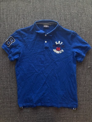 Superdry pike ~ vintage  - Sjukt eftertraktad Superdry piké ~ vintage modell | st 2XL på etiketten men passar bäst som L | färg blå | vintageplagg i bra skick | äldre modell som inte längre tillverkas och därför är svår att hitta | sällsynt 2000’s modell | OBS kan gå ner lite i pris vid snabb affär! 🏄