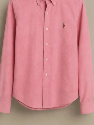 Rosa skjorta från Ralph Lauren - Säljer en rosa skjorta från Ralph Lauren i super slim fit. Skjortan har klassisk krage, knappar framtill och den ikoniska broderade loggan på bröstet. Tillverkad i mjuk bomull och har långa ärmar med knapp vid manschetten.