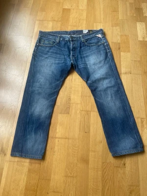 Blå raka jeans från replay  - Säljer ett par klassiska blå jeans med raka ben och snygga slitningar. Jeansen har fem fickor och normal midja. Skriv om ni har några funderingar eller nåt annat!