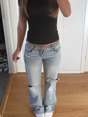 Ljusblå slitna raka jeans - Säljer ett par ljusblå jeans med raka ben och slitningar på både lår och knän. Jeansen har låg midja och klassisk femficksmodell. Materialet är denim i bomull och de har en avslappnad, trendig look. Jag är 168, men passar för något kortare och något längre💕