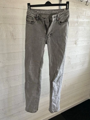 Grå mid wide jeans med raka ben - Snygga grå jeans med mid wide passform och raka ben. Klassisk femficksmodell med dragkedjegylf och bälteshällor. Jeansen har en ljusgrå tvätt och är tillverkade i denim, perfekt för en avslappnad och trendig look.